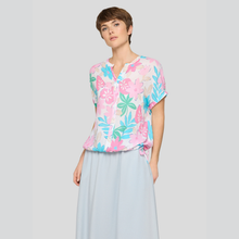 Load image into Gallery viewer, Woman wearing a colorful floral blouse and light blue skirt on a plain background