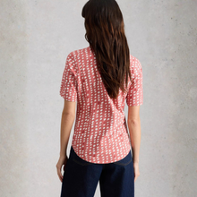 Load image into Gallery viewer, Person wearing a red patterned shirt and dark jeans against a gray background