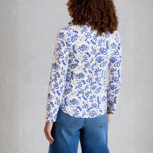 Load image into Gallery viewer, Person wearing a white shirt with blue floral pattern and blue jeans against a gray background