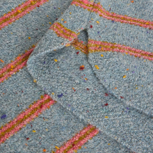 Load image into Gallery viewer, A close-up of a textured fabric with a heathered light blue base, decorated with diagonal stripes in pink, orange, yellow, and purple.