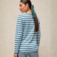Load image into Gallery viewer, A woman shown from the back wearing a blue and white striped long-sleeve shirt, paired with light blue jeans, against a neutral beige background.