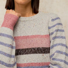 Load image into Gallery viewer, A close-up of a person wearing a fuzzy knit sweater with horizontal stripes in dusty pink, lavender, and dark brown over a speckled light gray base.