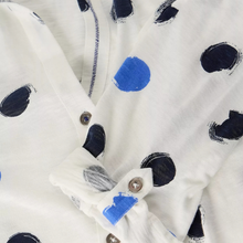 Load image into Gallery viewer, Close-up of a white button-front garment with a loose cuff, featuring irregular painted polka dots in dark navy and bright blue on a white fabric.
