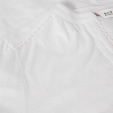 Load image into Gallery viewer, Close-up of a white textured fabric garment with a scalloped neckline and a small fabric label reading WHITE.