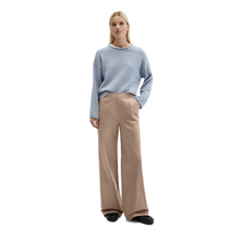 Load image into Gallery viewer, Woman wearing a light blue sweater and beige pants on a white background