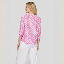 Load image into Gallery viewer, Woman wearing a pink patterned blouse and white pants on a plain background