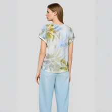 Load image into Gallery viewer, Woman wearing a floral blouse and light blue jeans on a plain background