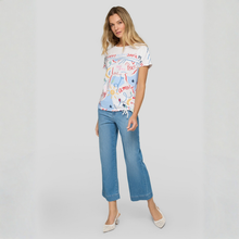 Load image into Gallery viewer, Woman wearing a colorful t-shirt and blue jeans on a gray background