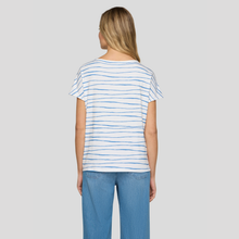 Load image into Gallery viewer, Woman wearing a white t-shirt with blue stripes and blue jeans on a gray background