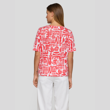 Load image into Gallery viewer, Rear of red & white print top on lady with white trousers