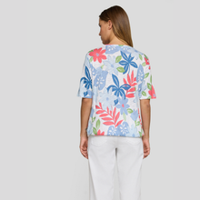 Load image into Gallery viewer, Woman wearing a colorful floral-patterned shirt on a plain background