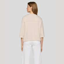 Load image into Gallery viewer, Woman wearing a beige sweater and white pants on a plain background