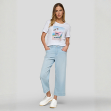 Load image into Gallery viewer, Woman wearing a white t-shirt with a graphic design and light blue jeans on a plain background