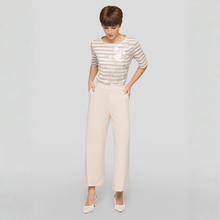 Load image into Gallery viewer, Woman wearing a striped top and beige pants on a gray background