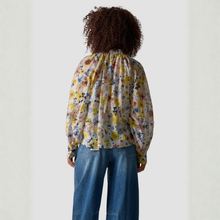 Load image into Gallery viewer, Person wearing a floral blouse and blue jeans against a white background