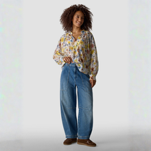 Load image into Gallery viewer, Woman wearing a floral blouse and blue jeans on a light gray background