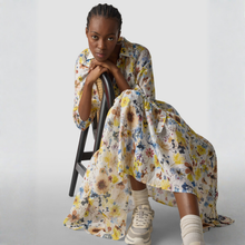 Load image into Gallery viewer, Woman sitting on a chair wearing a floral dress with a white background