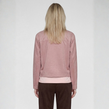 Load image into Gallery viewer, A woman viewed from behind wearing a dusty pink cropped long-sleeve top and dark brown pants against a light gray studio background.