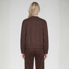 Load image into Gallery viewer, A model viewed from the back wearing a dark brown cropped jacket and matching brown trousers against a light gray studio background.