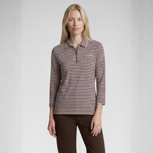 Load image into Gallery viewer, A woman modeling a long-sleeve polo shirt with thin brown and white horizontal stripes, featuring a partial button placket and a small embroidered chest logo, paired with dark brown pants against a light gray studio background.