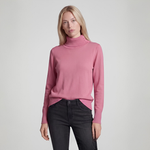 Load image into Gallery viewer, A woman modeling a dusty pink mock neck knit sweater with black jeans, standing against a light gray studio background.