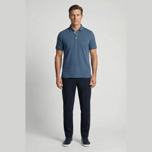 Load image into Gallery viewer, Man wearing a blue polo shirt and dark pants on a light gray background
