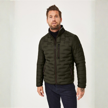 Load image into Gallery viewer, A man wearing an olive green quilted puffer jacket over a black turtleneck and dark blue jeans, standing against a plain light gray studio background.