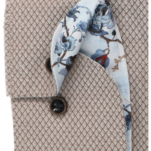 Load image into Gallery viewer, Close-up of a textured beige shirt with a patterned necktie featuring blue flowers, brown branches, and a small red accent on a white background.