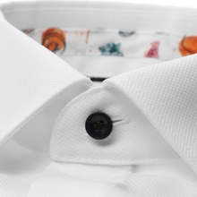 Load image into Gallery viewer, Close-up of a white shirt with a black button, floral-patterned collar background