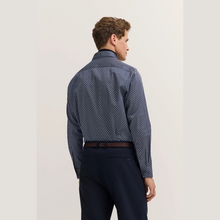 Load image into Gallery viewer, Man wearing a patterned blue shirt and dark pants on a light background