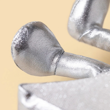 Load image into Gallery viewer, Close-up of a metallic silver textured object with a rounded end and cylindrical stem, shown against a warm beige background.