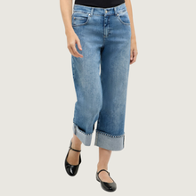 Load image into Gallery viewer, Light blue jeans with rolled-up cuffs worn by a person on a white background