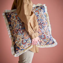 Load image into Gallery viewer, Person holding a decorative pillow with intricate patterns and fringes against a pink background
