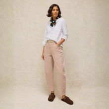 Load image into Gallery viewer, A woman stands against a warm beige studio backdrop wearing a white button-up shirt, light beige trousers, dark brown slip-on shoes, and a patterned teal scarf.