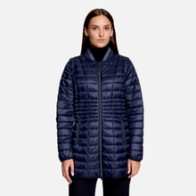 Load image into Gallery viewer, A woman wearing a navy blue quilted puffer jacket with a stand-up collar and front zipper, photographed against a light gray studio background.