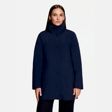 Load image into Gallery viewer, A woman modeling a dark navy blue mid-length coat with a high stand collar and front buttons, set against a plain light gray studio background.