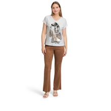 Load image into Gallery viewer, Woman wearing a white t-shirt with a graphic design and brown pants on a white background