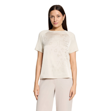 Load image into Gallery viewer, A woman modeling a light beige short-sleeve t-shirt with tonal graphic lettering and matching light beige trousers, set against a plain white background.