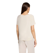 Load image into Gallery viewer, A woman shown from the back wearing a short-sleeve cream-colored top and light beige pants against a plain white background.