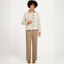 Load image into Gallery viewer, A model stands against a plain white studio background wearing a textured cream jacket over a white knit top, paired with straight-leg beige trousers and brown shoes.