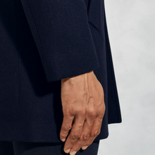 Load image into Gallery viewer, Hand wearing a dark blue coat against a light gray background