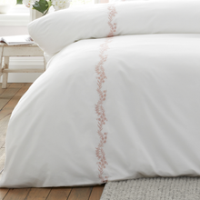 Load image into Gallery viewer, White bedding set with floral embroidery on a wooden floor.