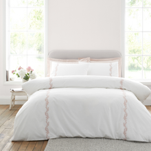 Load image into Gallery viewer, White bedding set with subtle design on a bed in a bright room with large windows.