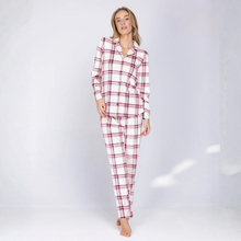 Load image into Gallery viewer, A woman modeling a two-piece plaid pajama set consisting of a long-sleeve button-up shirt and matching pants, in a white base with a red and dark blue plaid pattern, set against a light gray studio background.