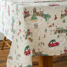 Load image into Gallery viewer, Tablecloth with Christmas-themed design featuring trees, cars, and people on a wooden table.
