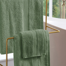 Load image into Gallery viewer, Green towels hanging on a gold towel rack in a bathroom.