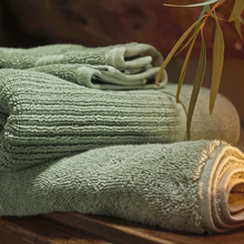 Load image into Gallery viewer, Stack of green towels on a wooden surface with a blurred background