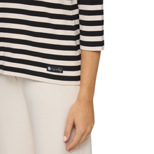 Load image into Gallery viewer, Woman wearing a black and white striped shirt with a visible brand logo on a white background