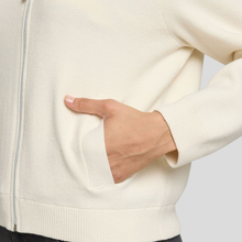 Load image into Gallery viewer, Close-up of a person wearing a cream-colored jacket with a hand in the pocket against a light gray background