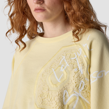 Load image into Gallery viewer, Person wearing a light yellow sweater with lace details and text on a plain background